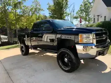 Black lifted pickup truck parked in a driveway on a sunny day