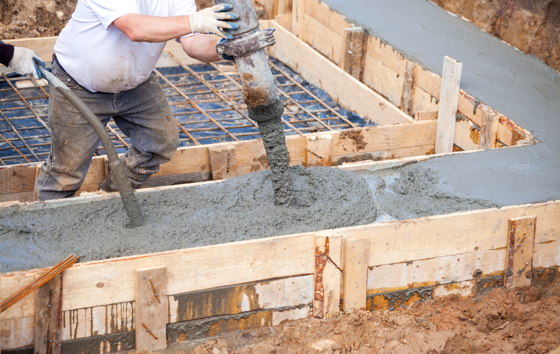 A man is pouring concrete into a wooden frame.