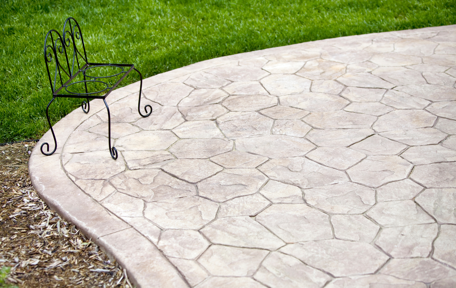 A chair is sitting on a concrete patio next to a lawn.