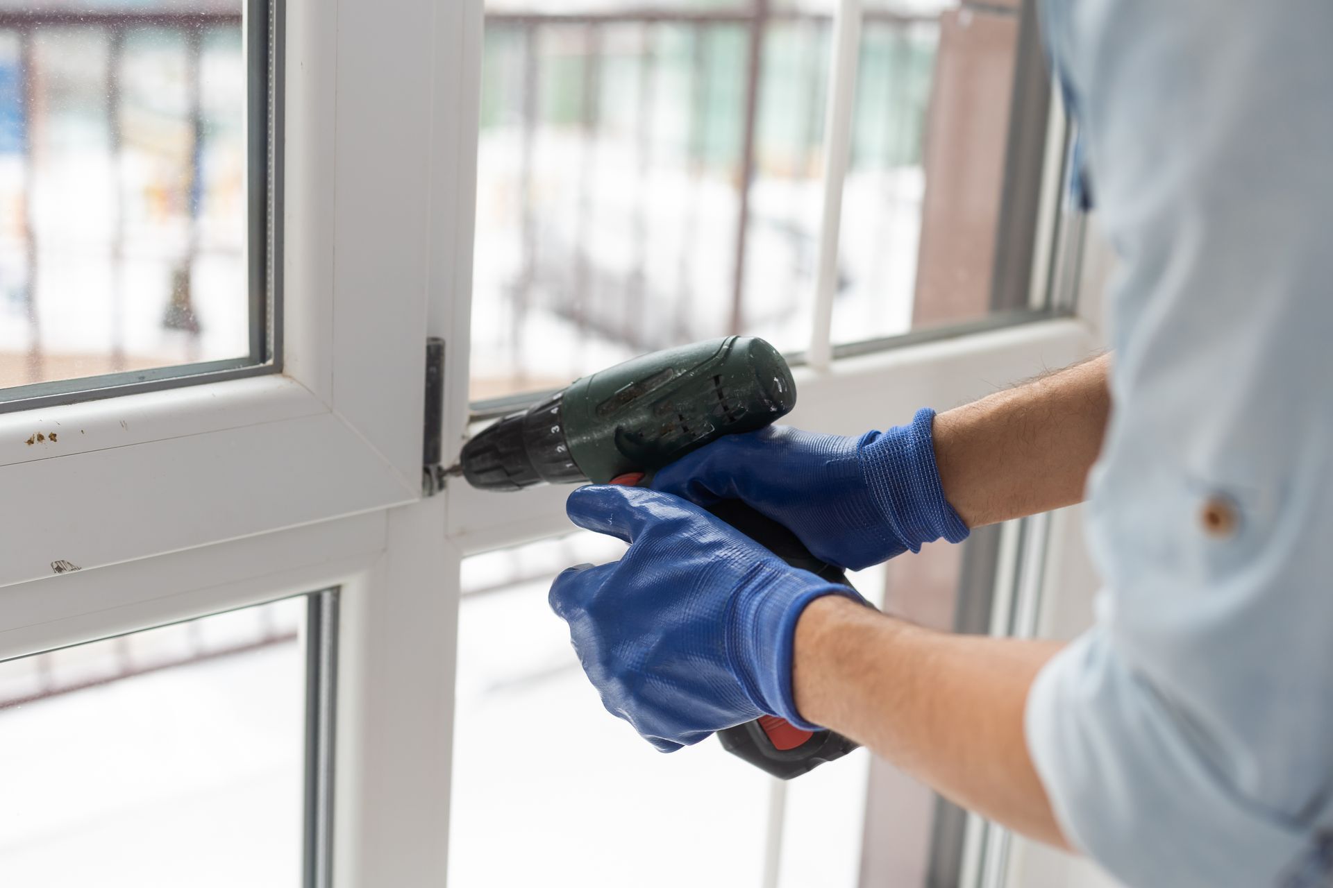 Person in Blue Gloves Uses a Drill to Repair a White Window — Lunny's Carpentry In Dubbo, NSW