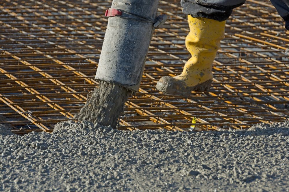 Concrete Being Poured from A Hose onto A Metal Grid — Lunny's Carpentry In Maroochydore, QLD