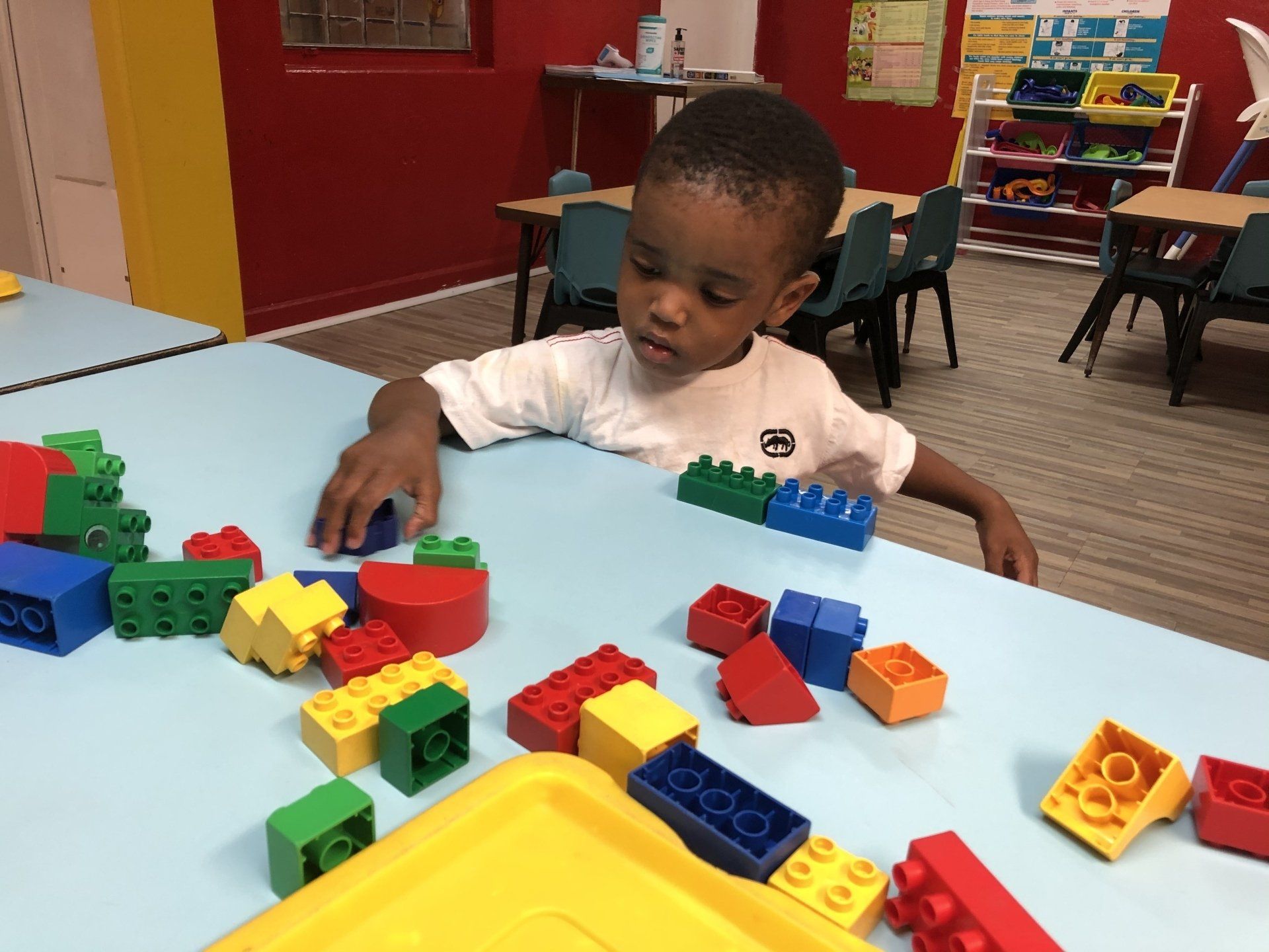 A young boy is playing with lego blocks at a table.