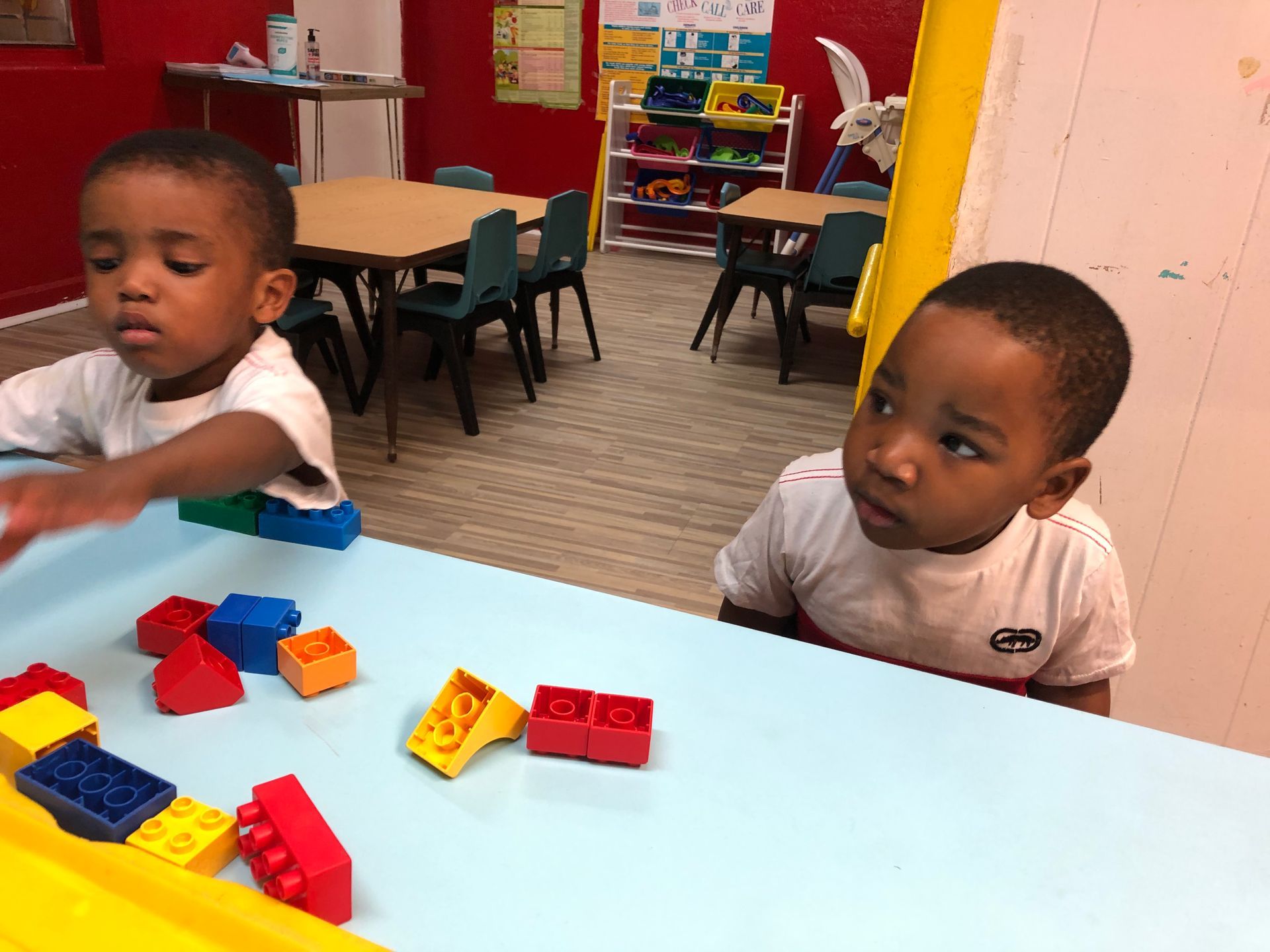 Two young boys are playing with lego blocks at a table.