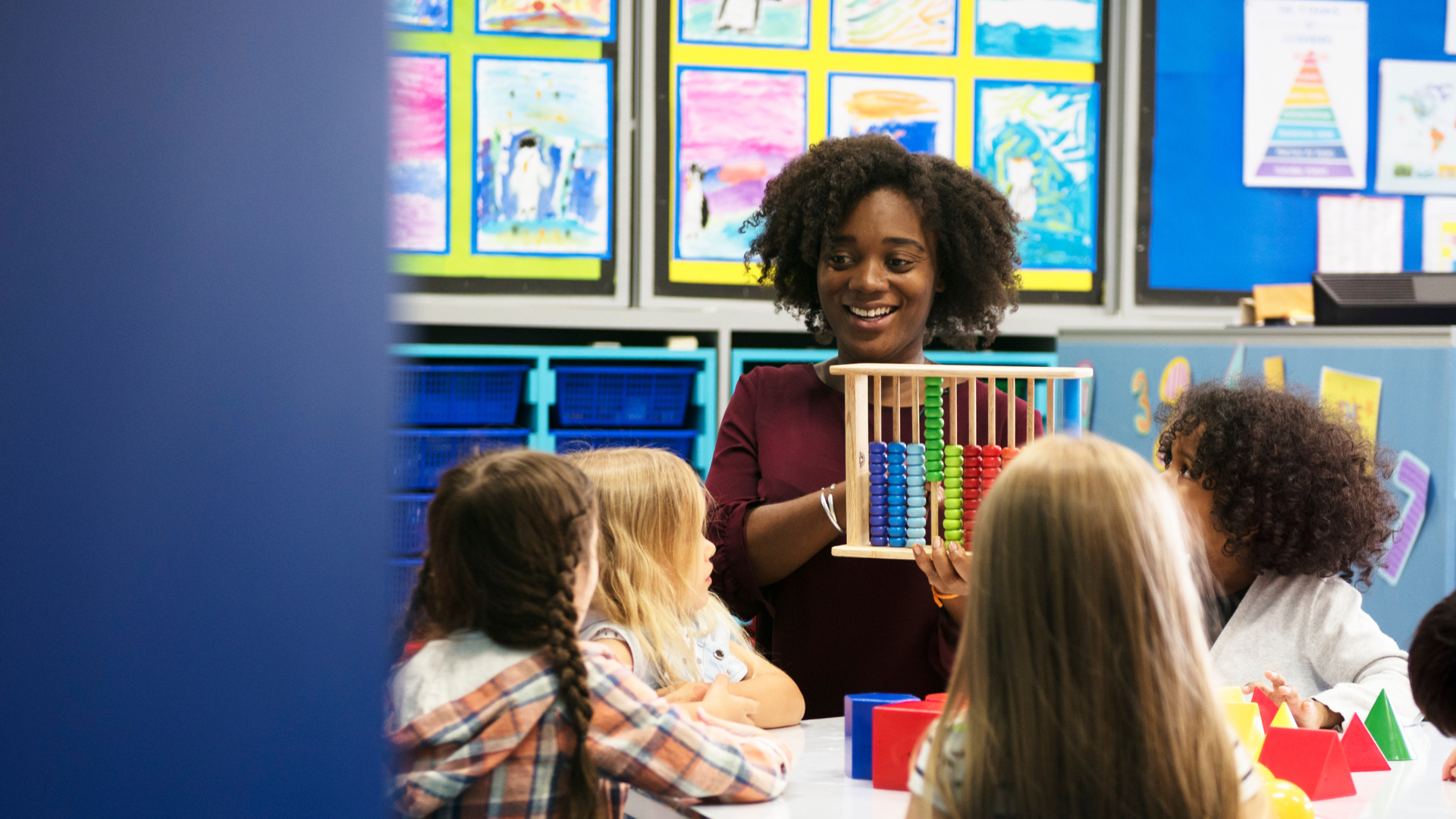 Teacher showing children an abacus in a classroom.