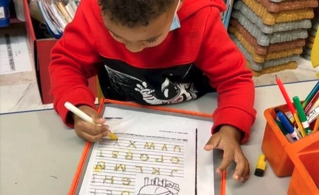 A young boy is writing on a piece of paper with a marker.