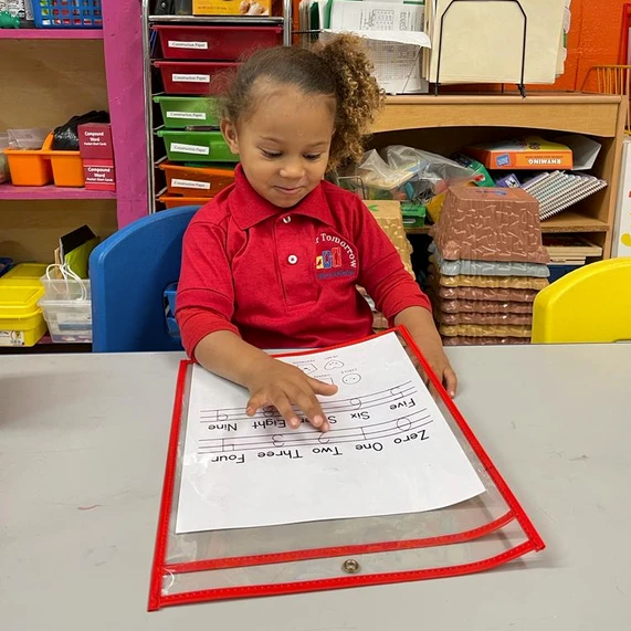 A little girl in a red shirt is sitting at a table