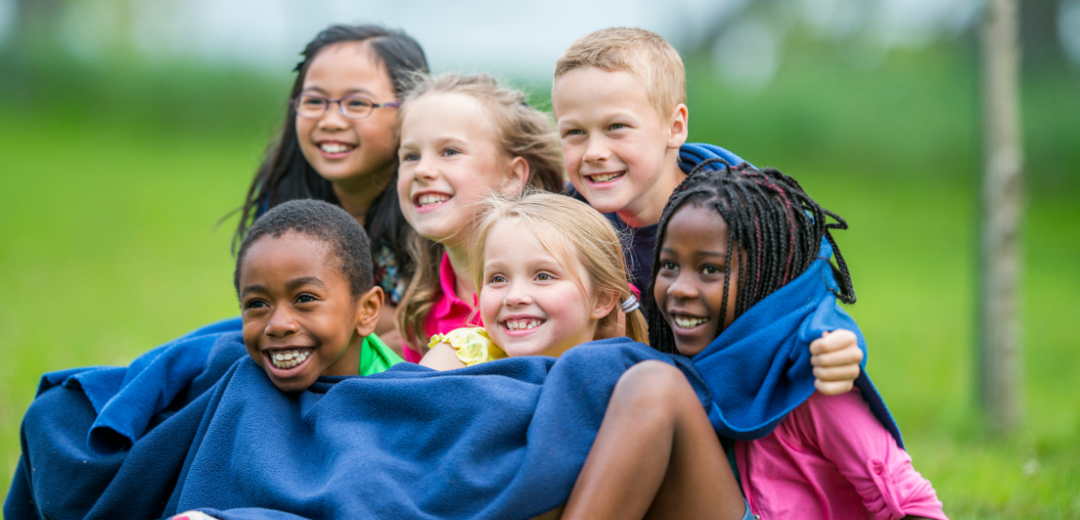 A group of children are sitting on top of each other in a park.