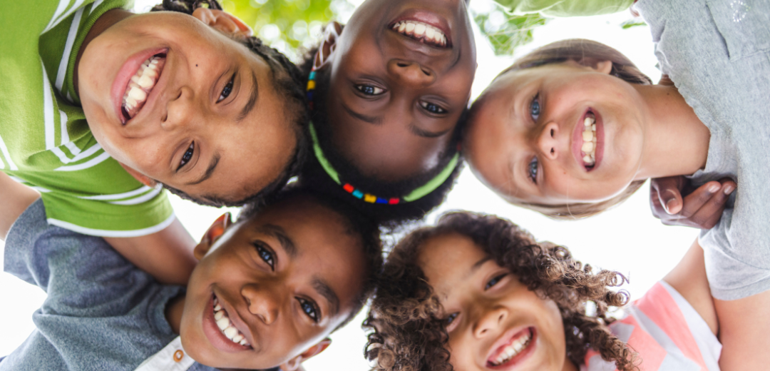 A group of children are standing in a circle and smiling.