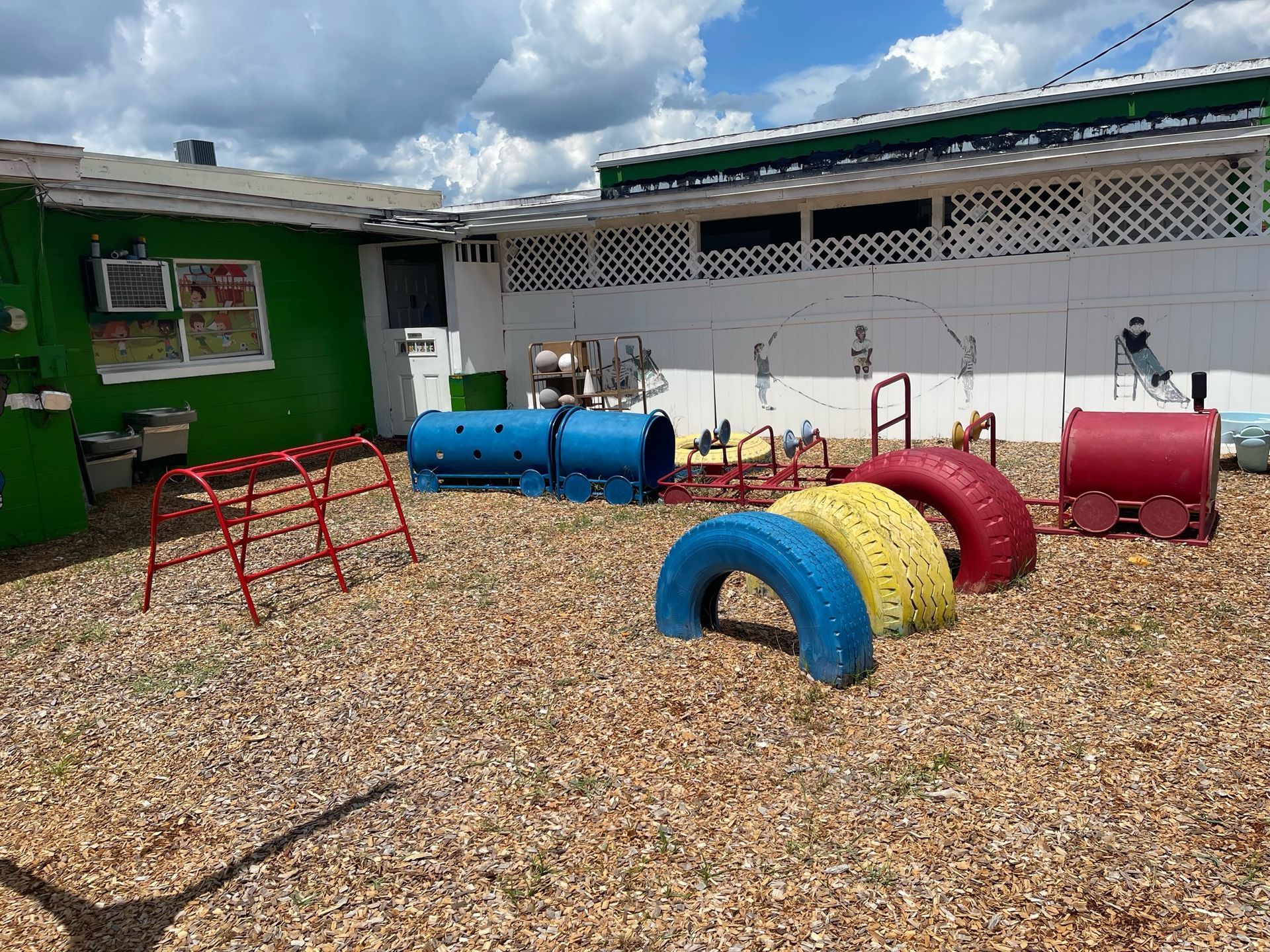 A colorful playground with a green building in the background.