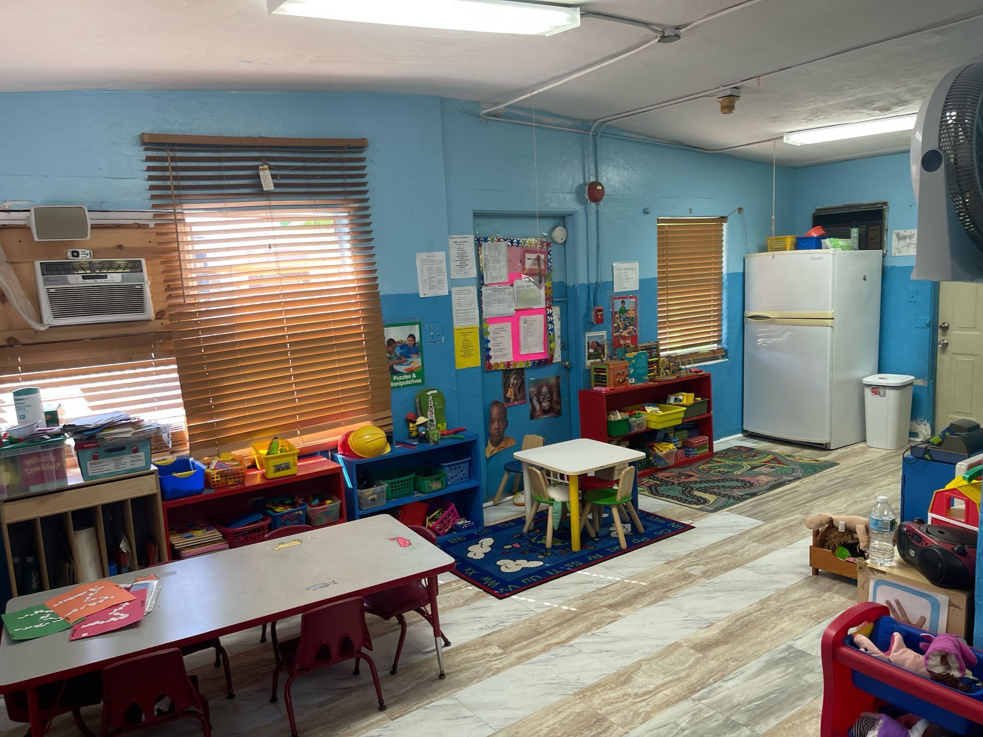 A classroom with tables and chairs and a refrigerator.