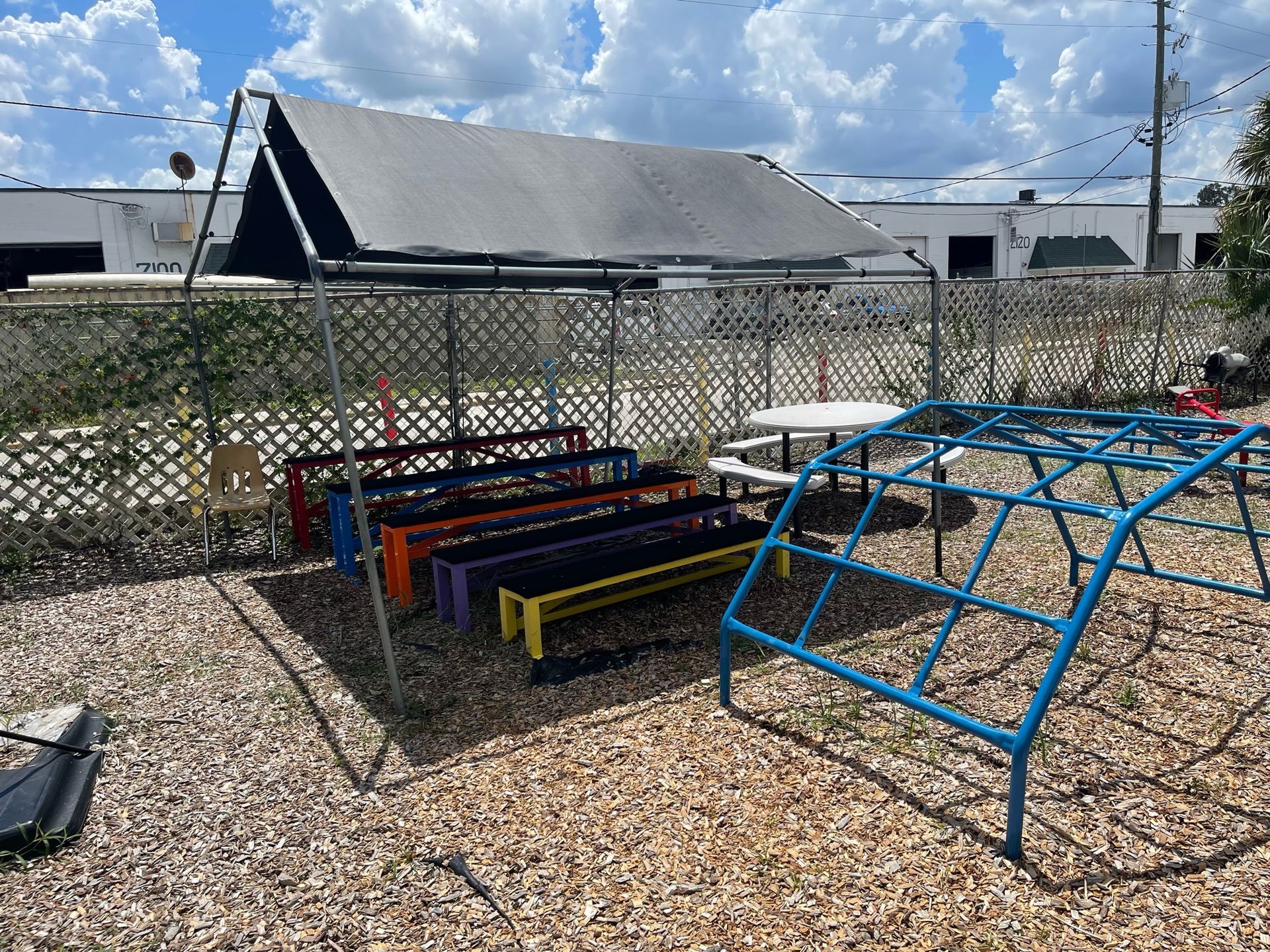 A playground with a monkey bars , benches , and tables.