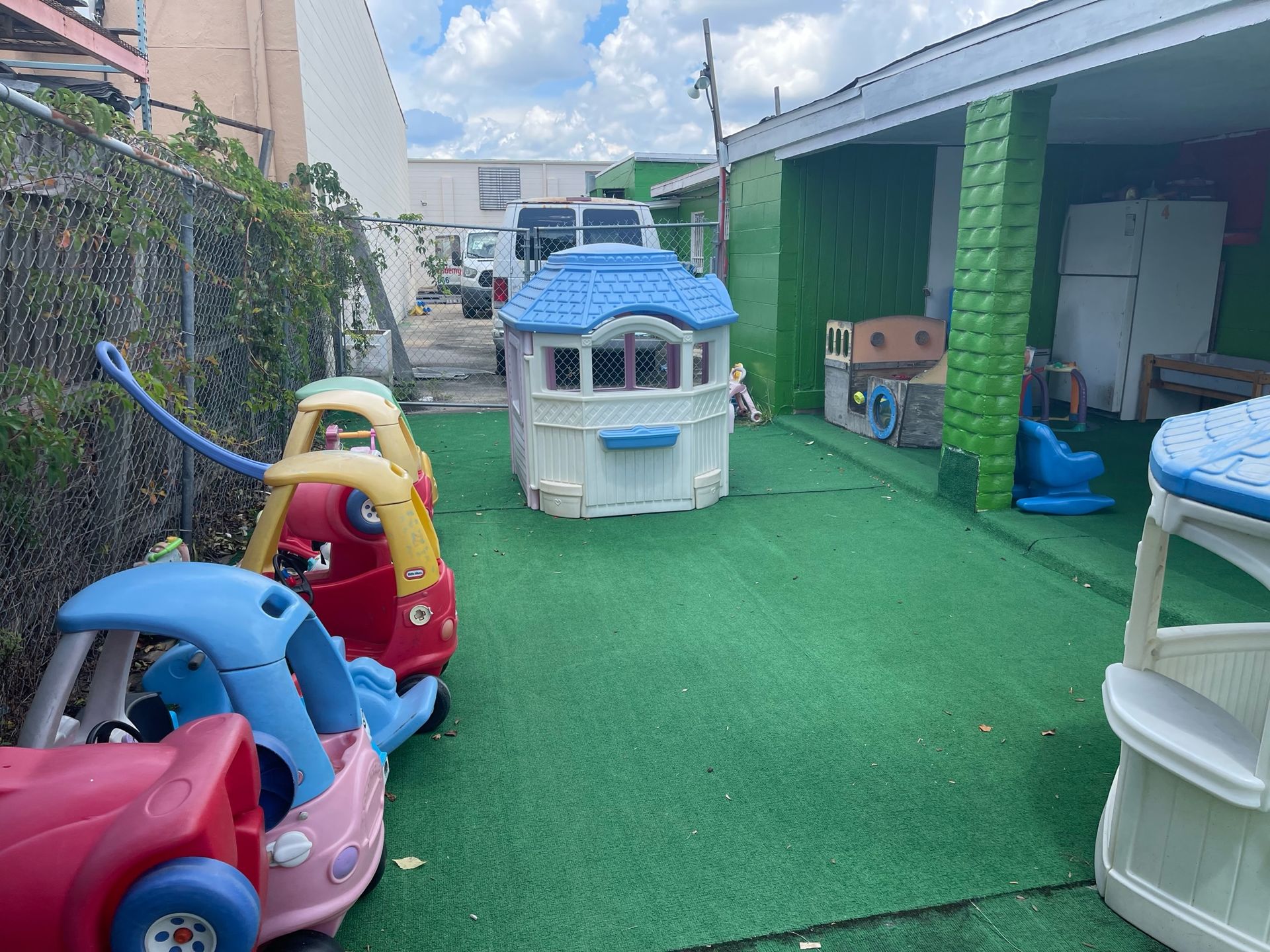 A bunch of toy cars and houses are sitting on top of a lush green lawn.