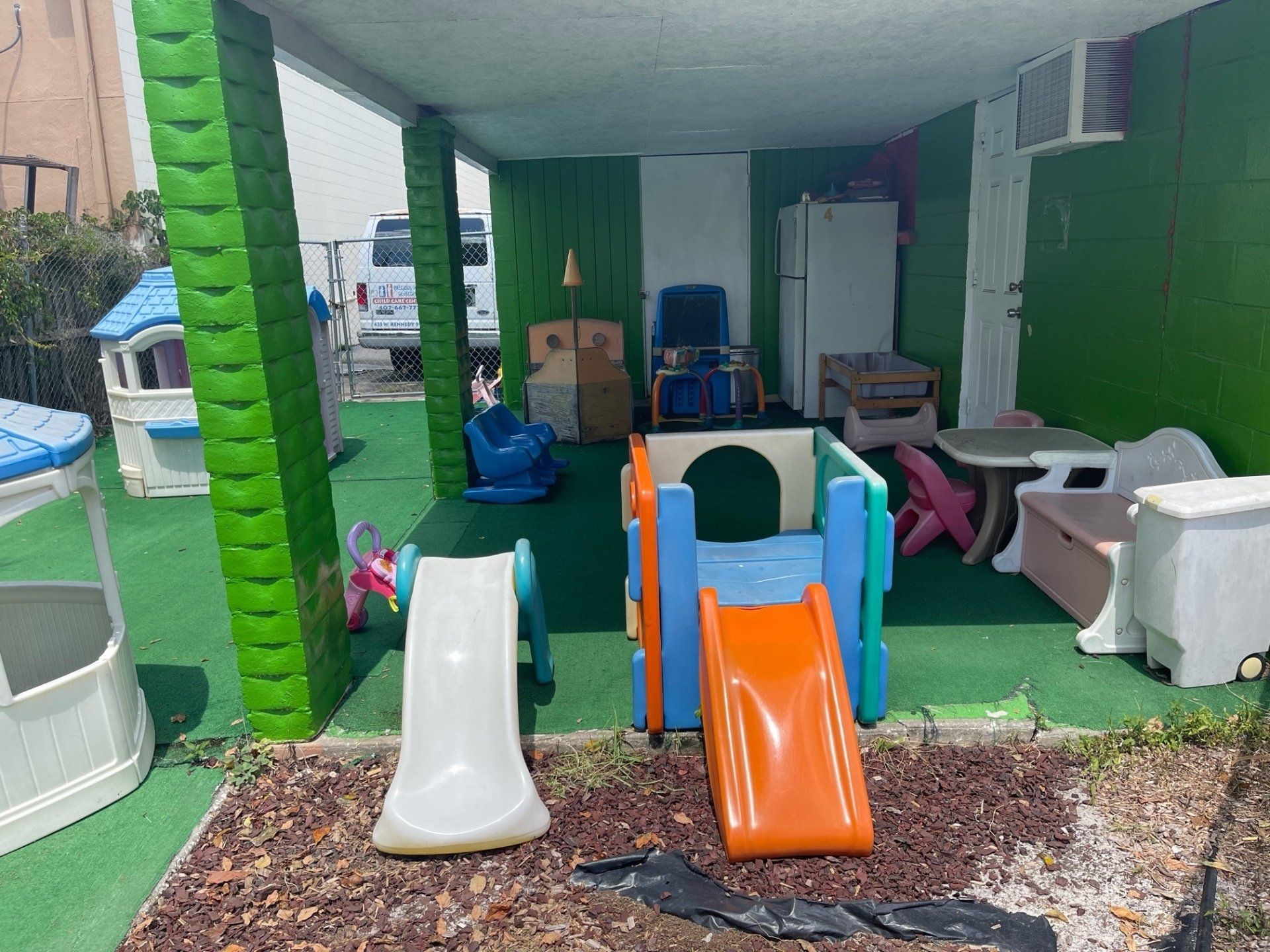 A playground with a slide , swings , tables and chairs.