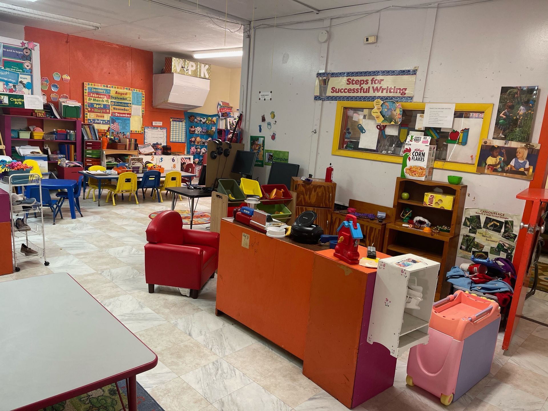 A classroom filled with tables , chairs , and toys.