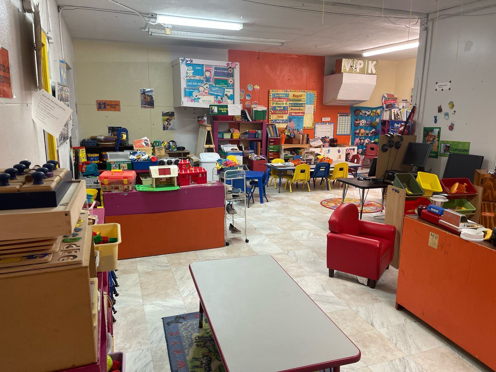 A classroom filled with lots of toys and tables and chairs.
