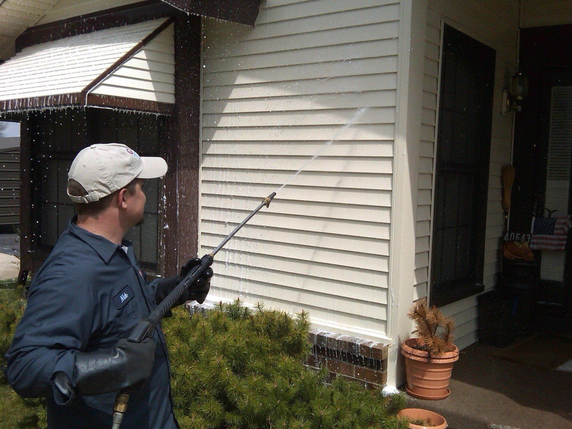 A man is spraying water on the side of a house