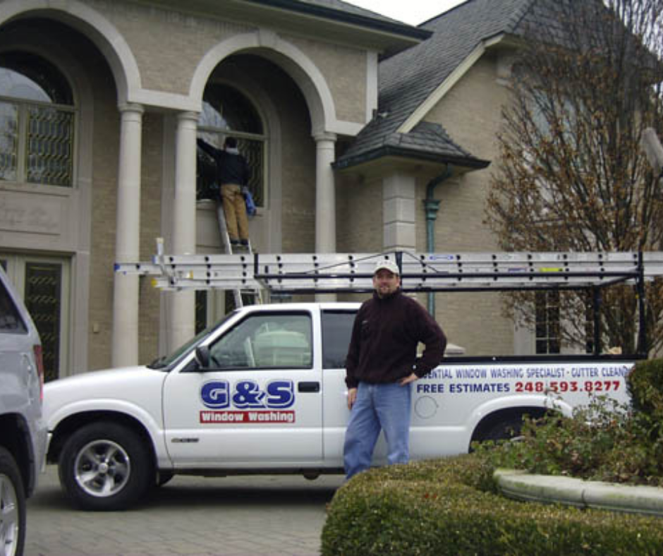 A g & s truck is parked in front of a house