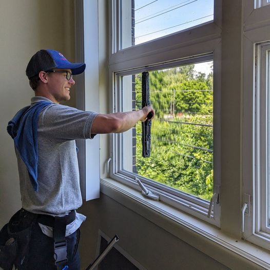A man is cleaning a window with a squeegee.