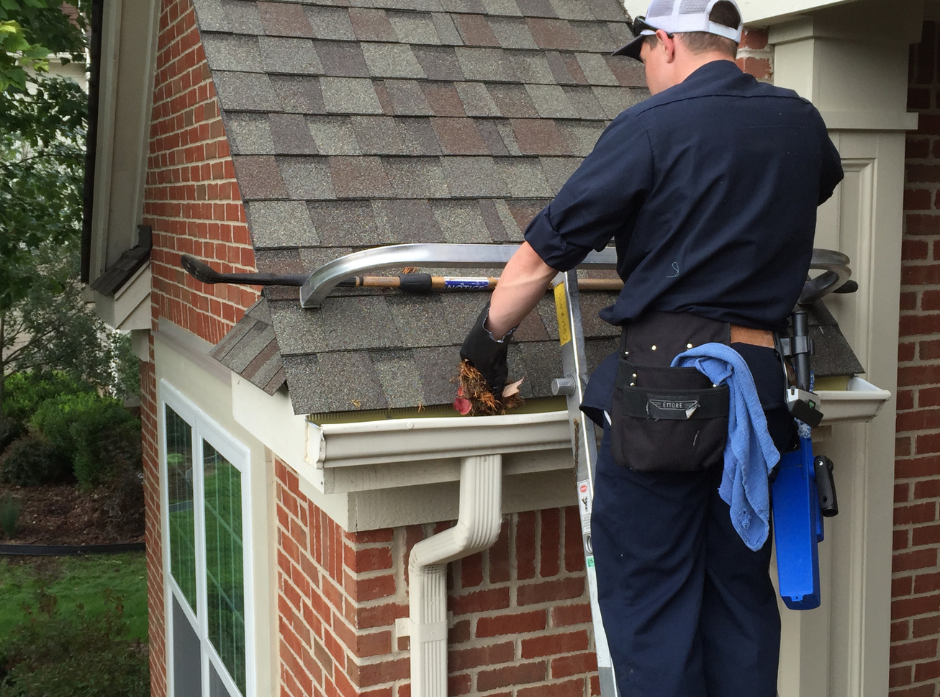 A man is standing on a ladder working on a roof.