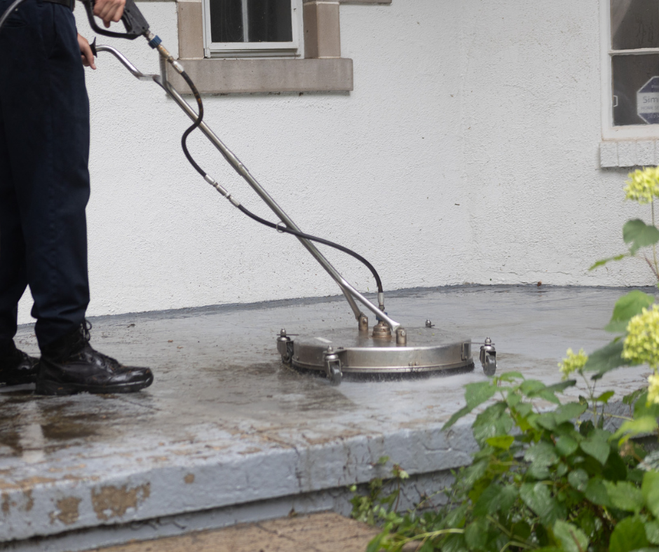 A man is using a high pressure washer to clean a sidewalk