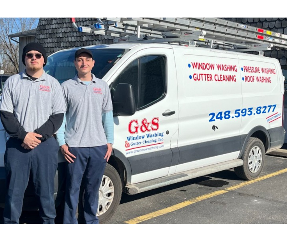 Two men are standing in front of a g & s van.