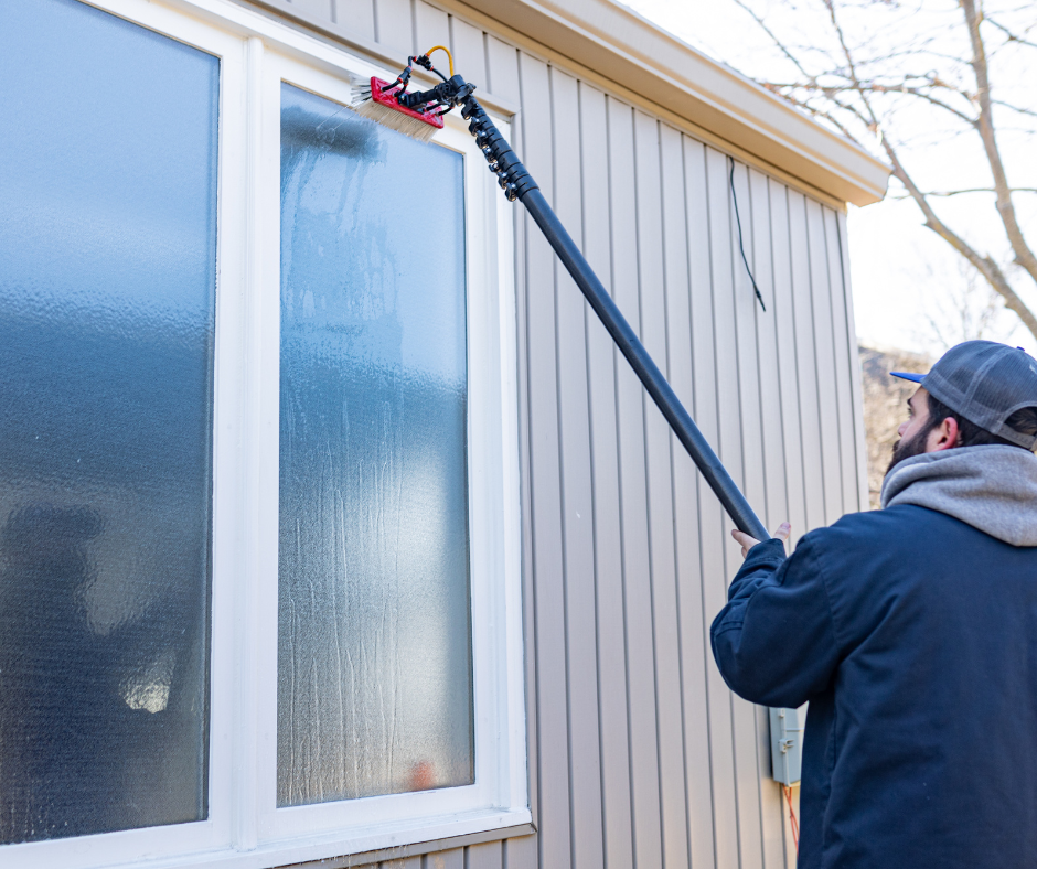 A man is cleaning a window with a long pole