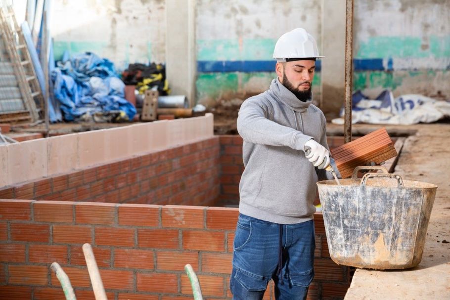 Worker in a hard hat spreading mortar on a brick wall at a construction site