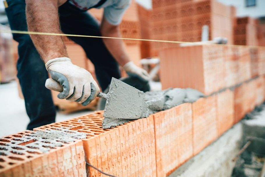 Worker spreading mortar on a brick wall during construction