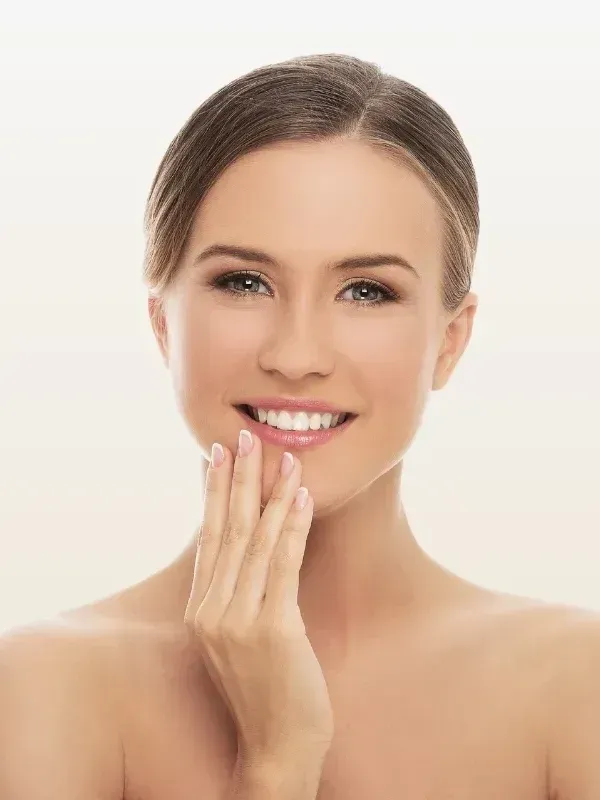 The woman is smiling and touching her face with her hand.
