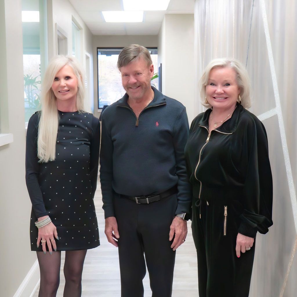 A man and two women are posing for a picture in a hallway