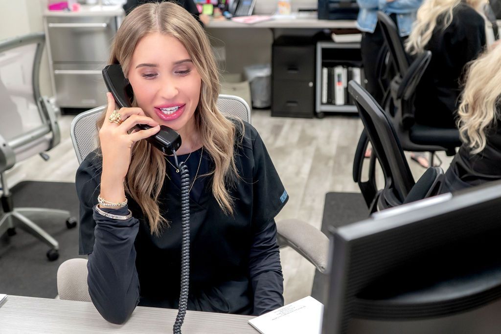 A woman is sitting at a desk talking on a phone.