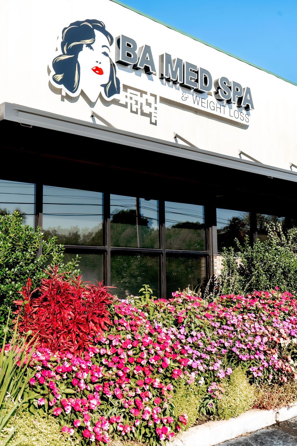 A building with a woman 's face on it and flowers in front of it.