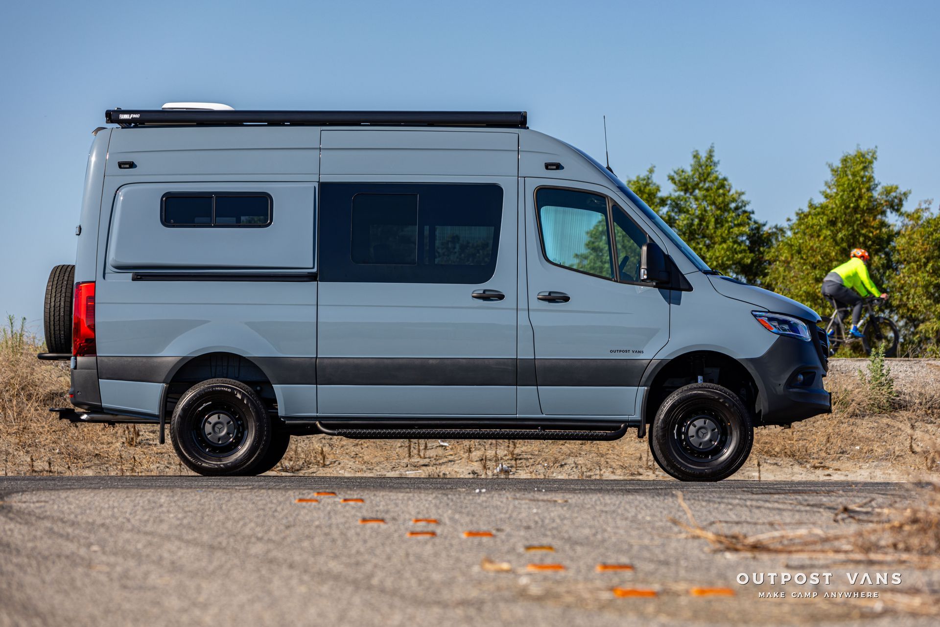 A gray van is parked on the side of the road next to a field.