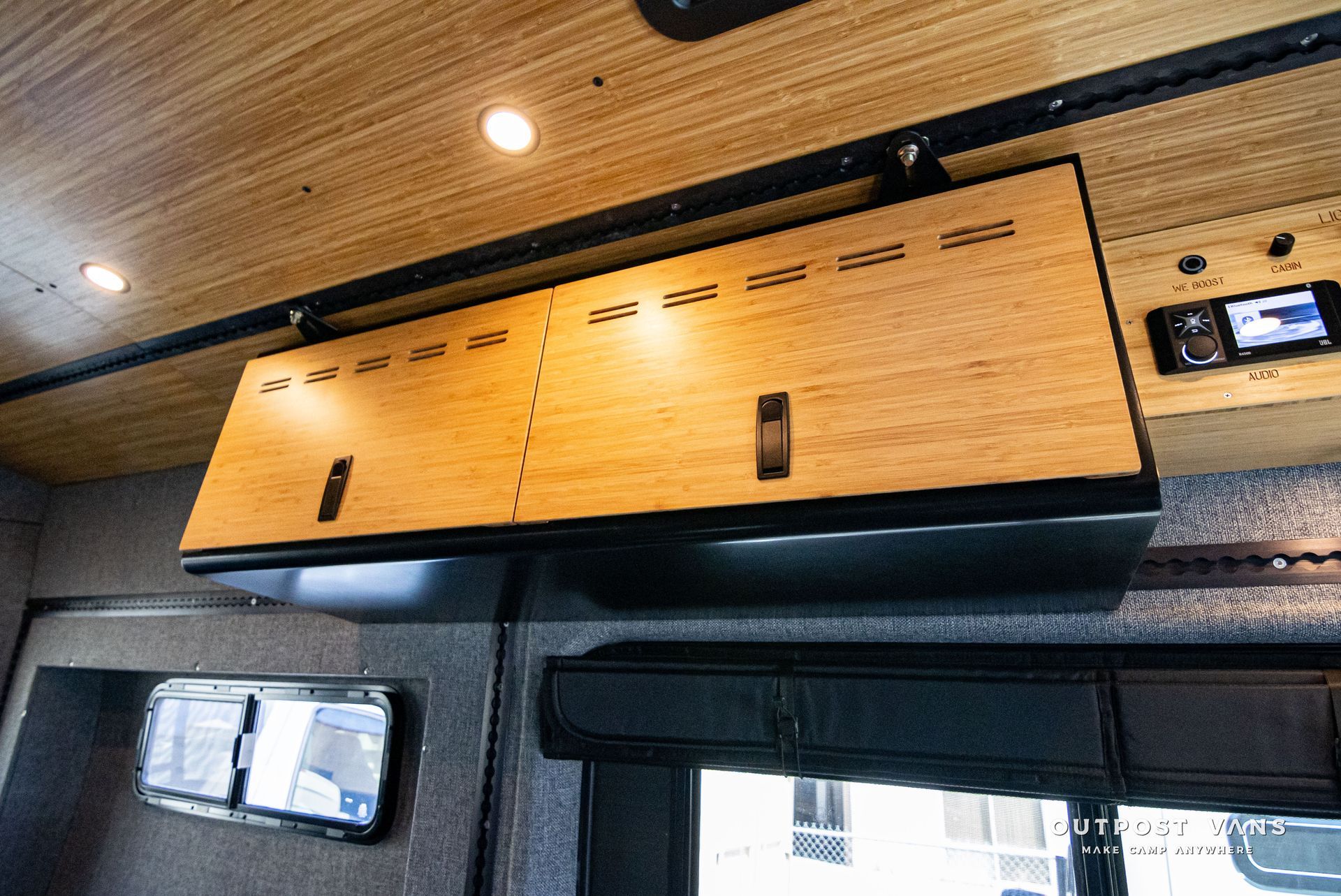A wooden cabinet is hanging from the ceiling of a van.