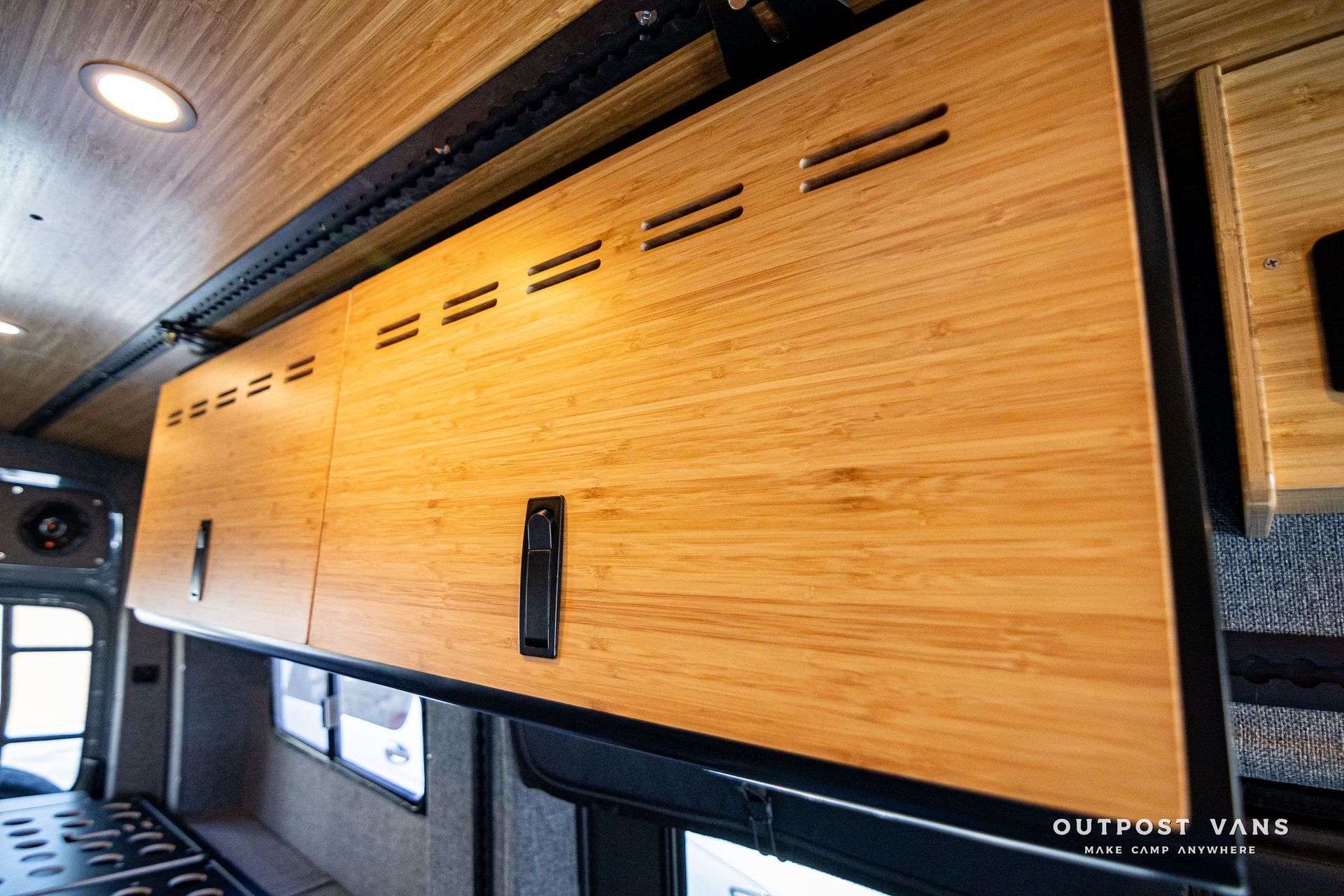 A wooden cabinet is hanging from the ceiling of a van.