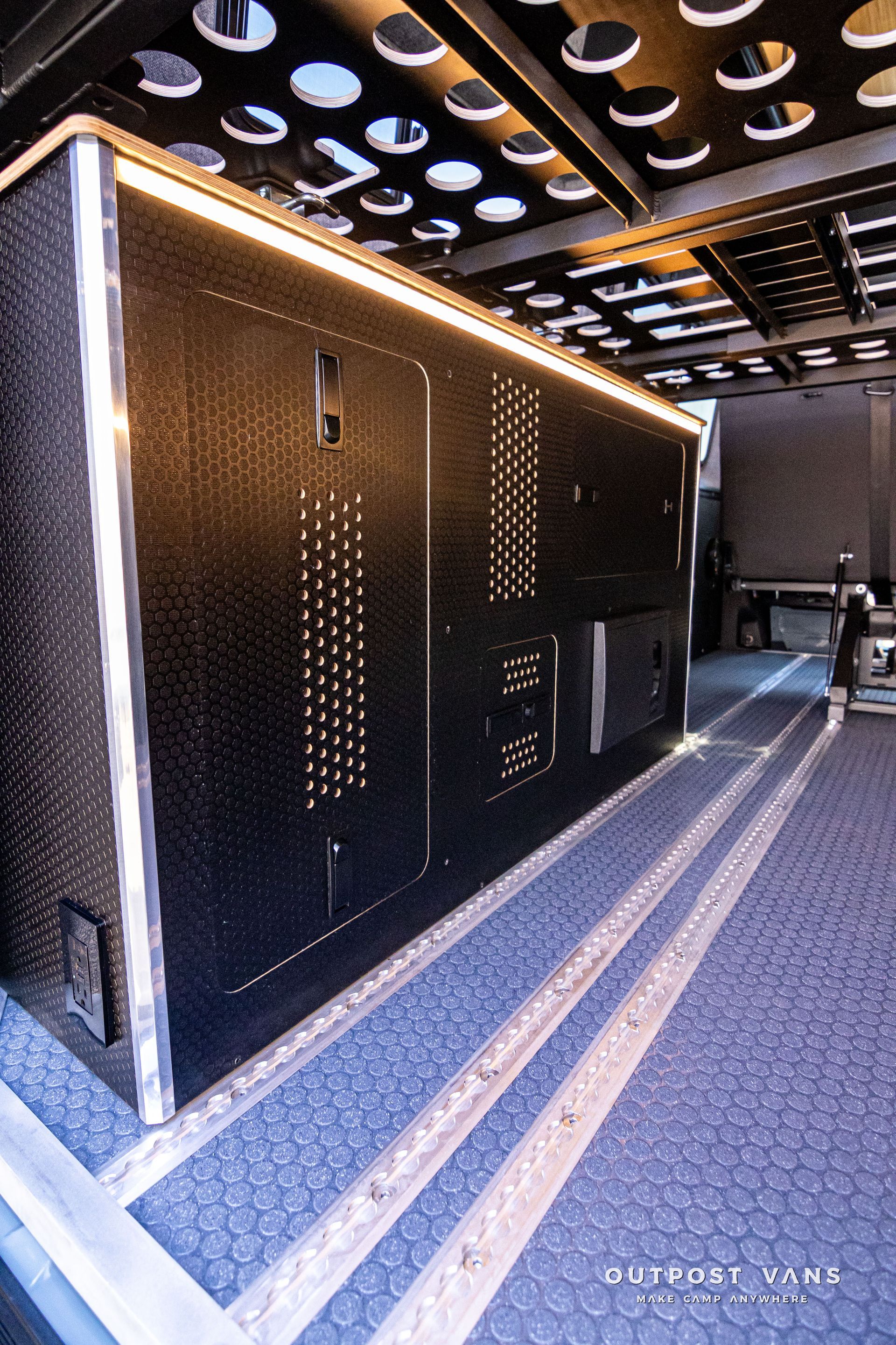 A black box with holes in it is sitting on a carpeted floor.