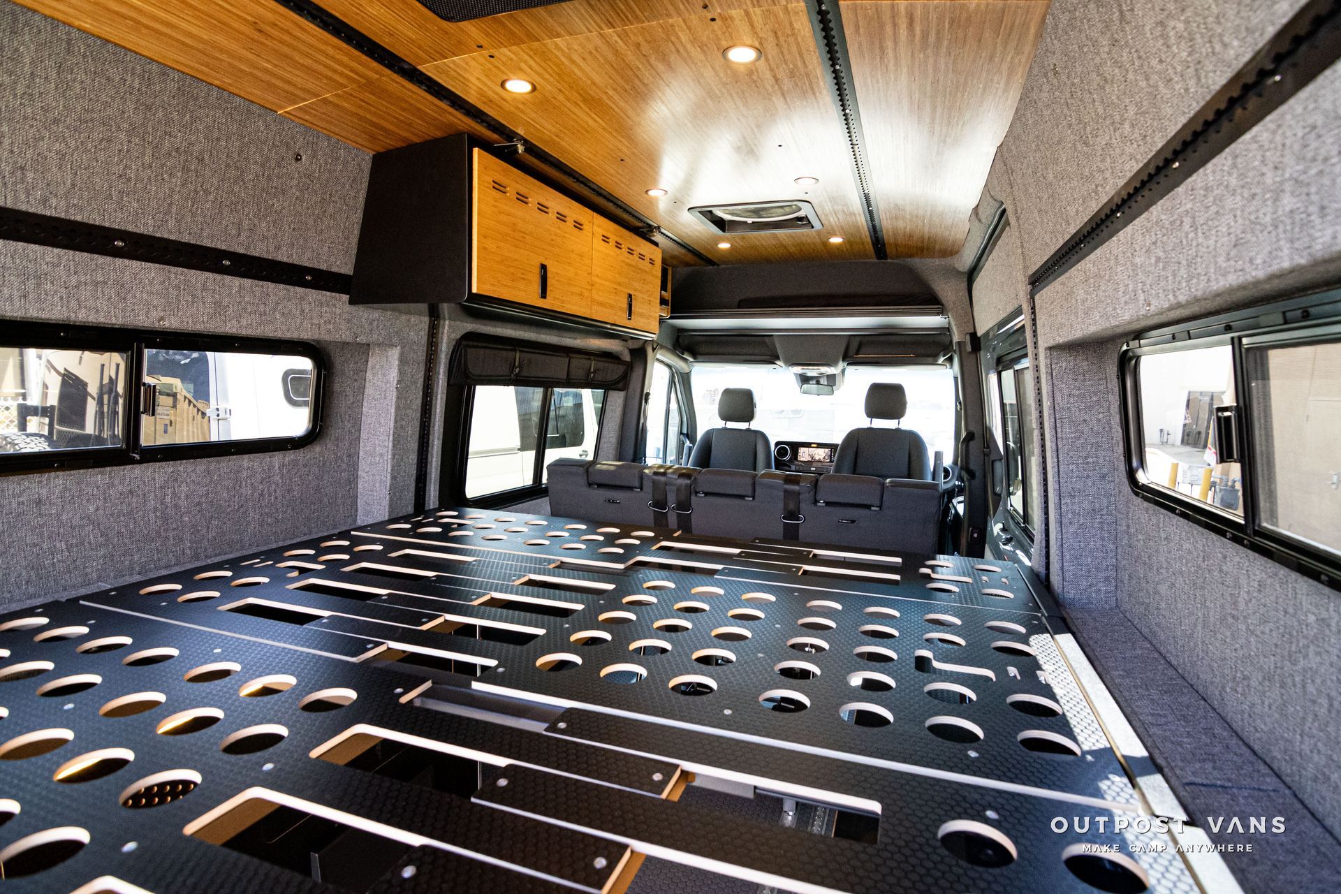 The inside of a van with a bed and chairs.