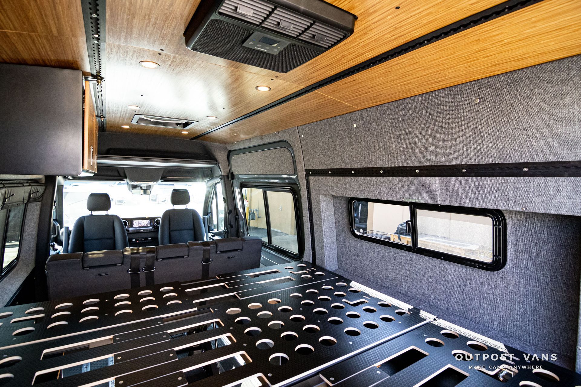 The inside of a van with a bed and a ceiling fan.