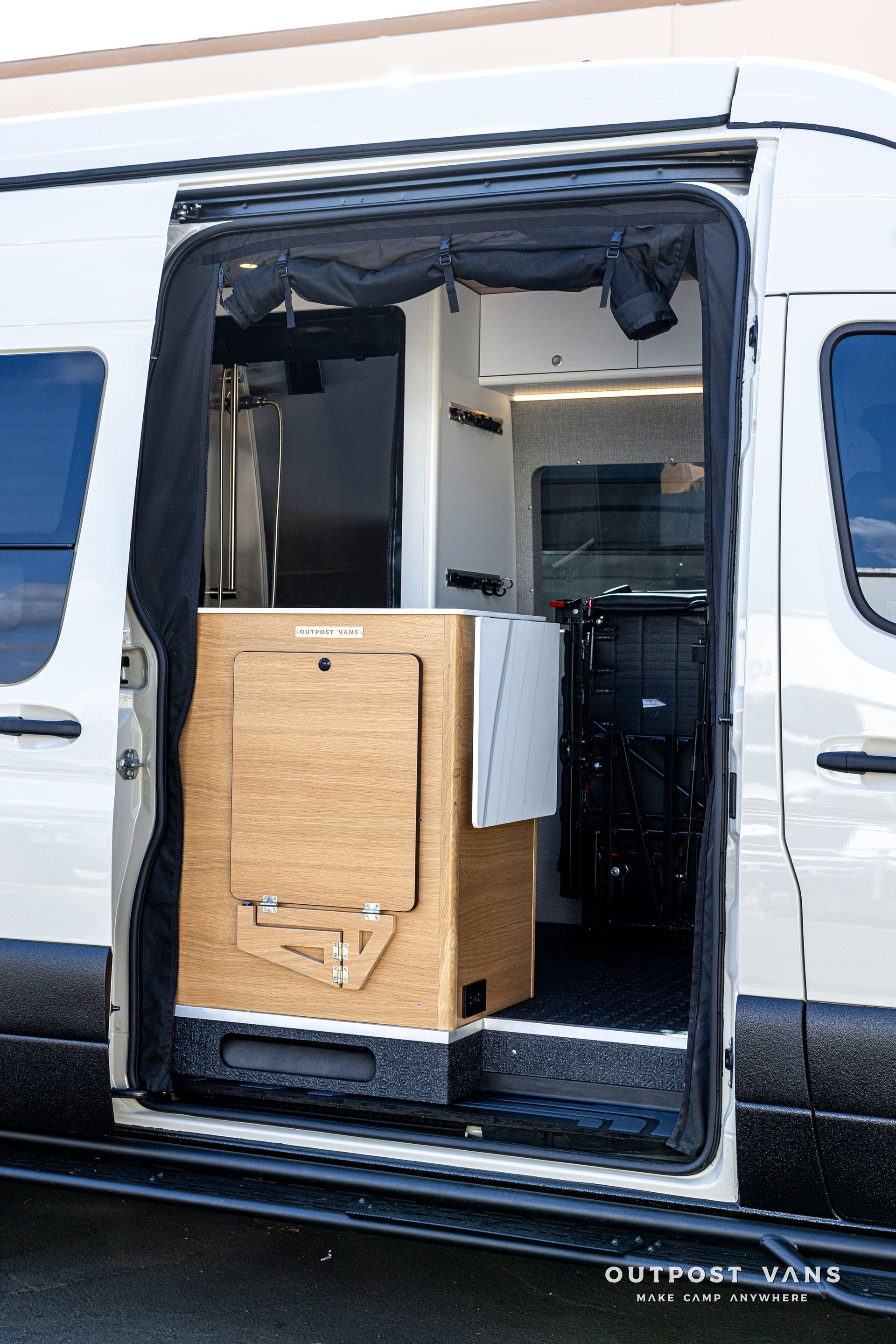 A white van with the door open and a wooden cabinet in the back.