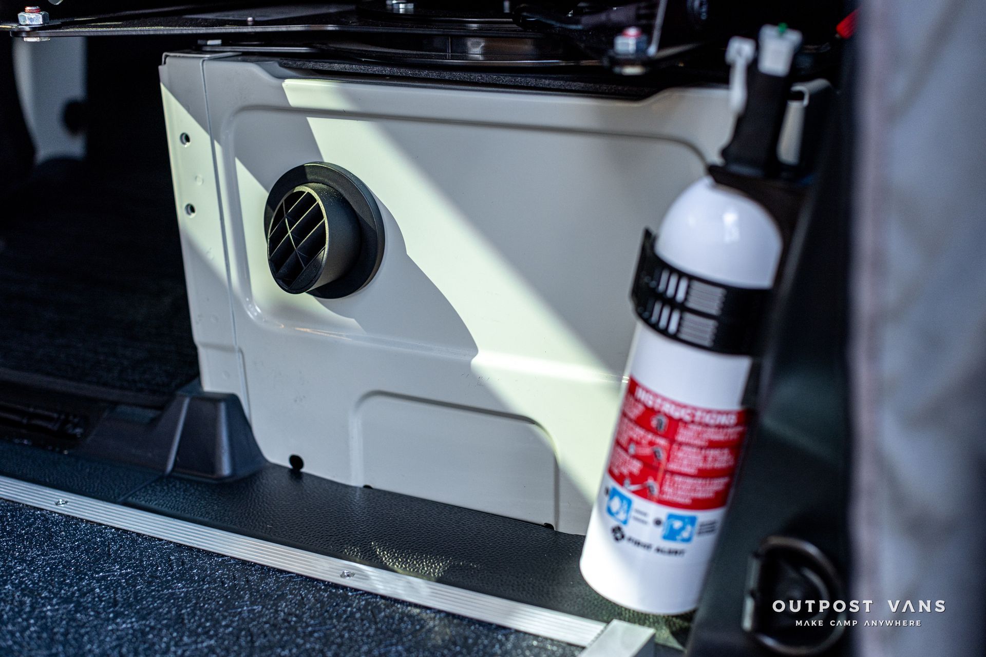 A fire extinguisher is hanging from the side of a car.