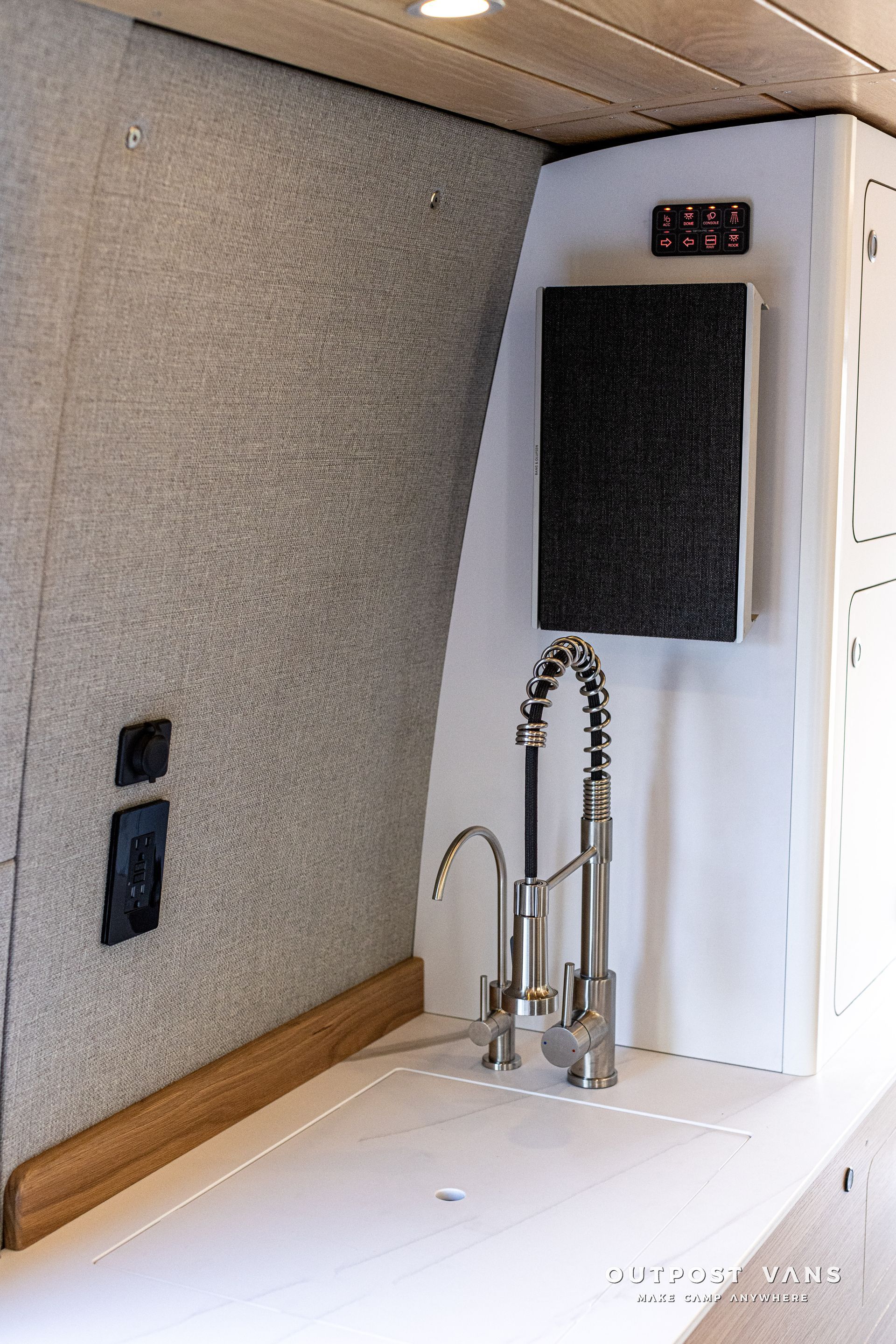 A kitchen sink with a faucet and a speaker on the wall.