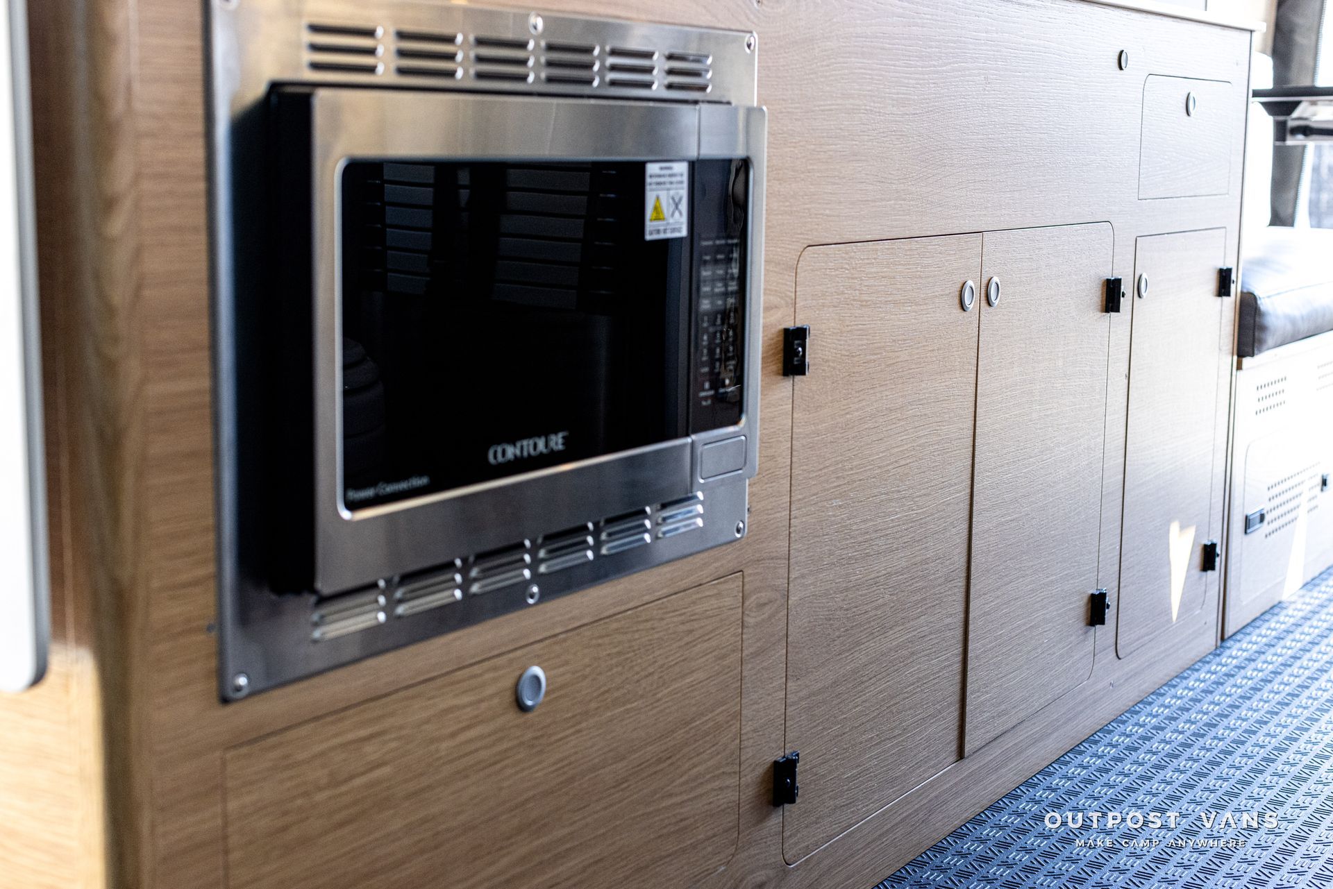 A stainless steel microwave oven is mounted on a wooden cabinet.