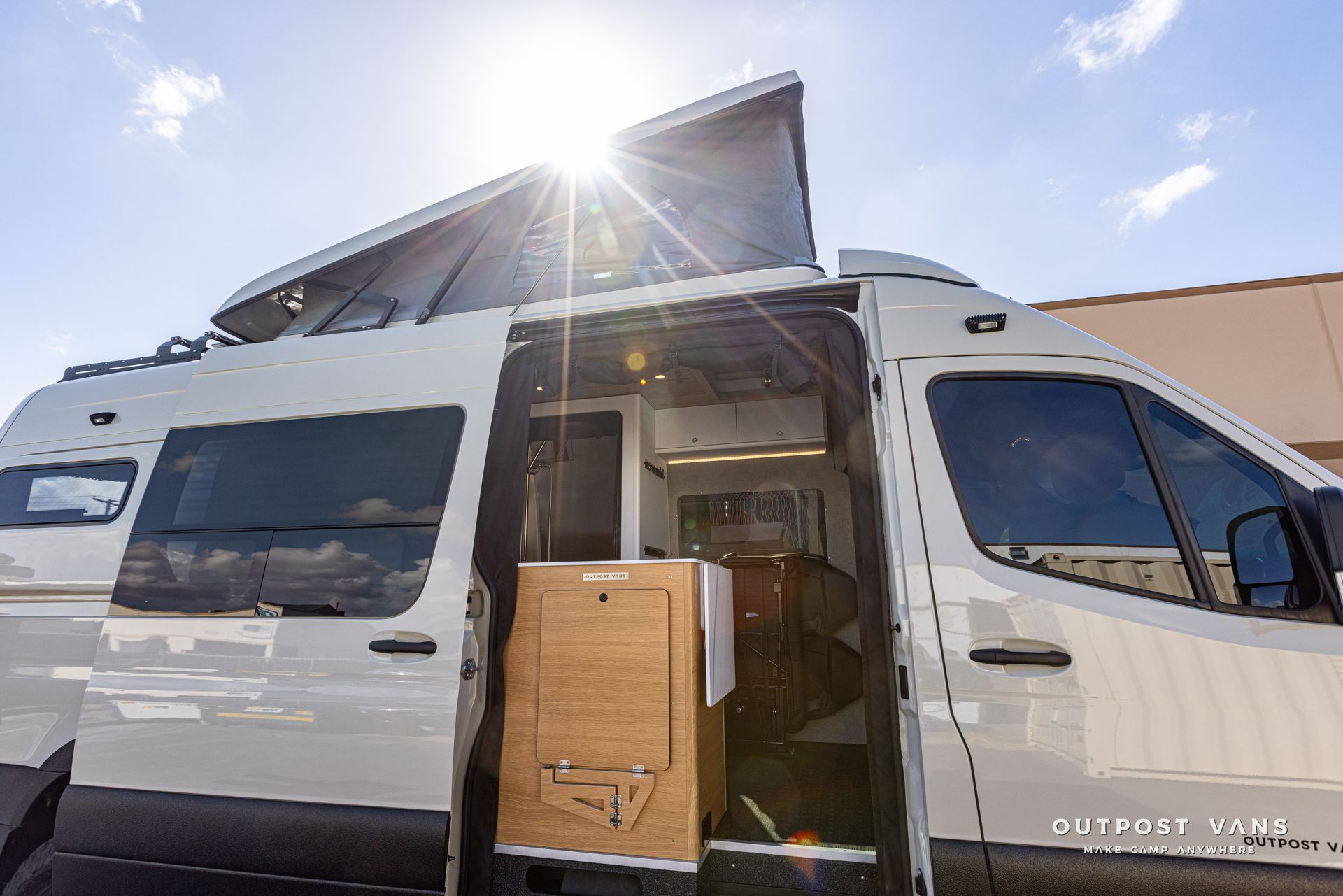 A white van with the door open and the sun shining through the windows.
