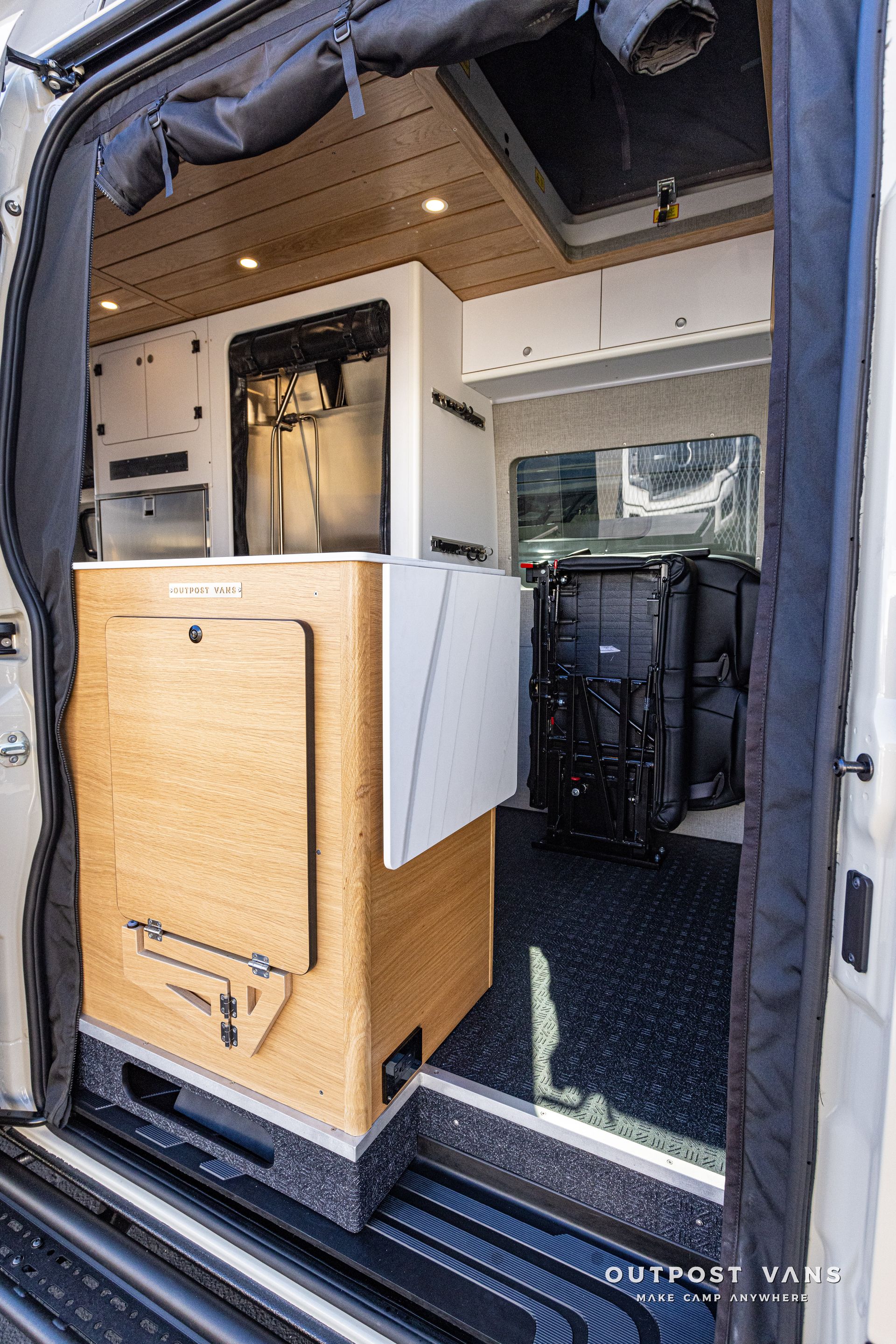 The inside of a van with a table and a refrigerator.