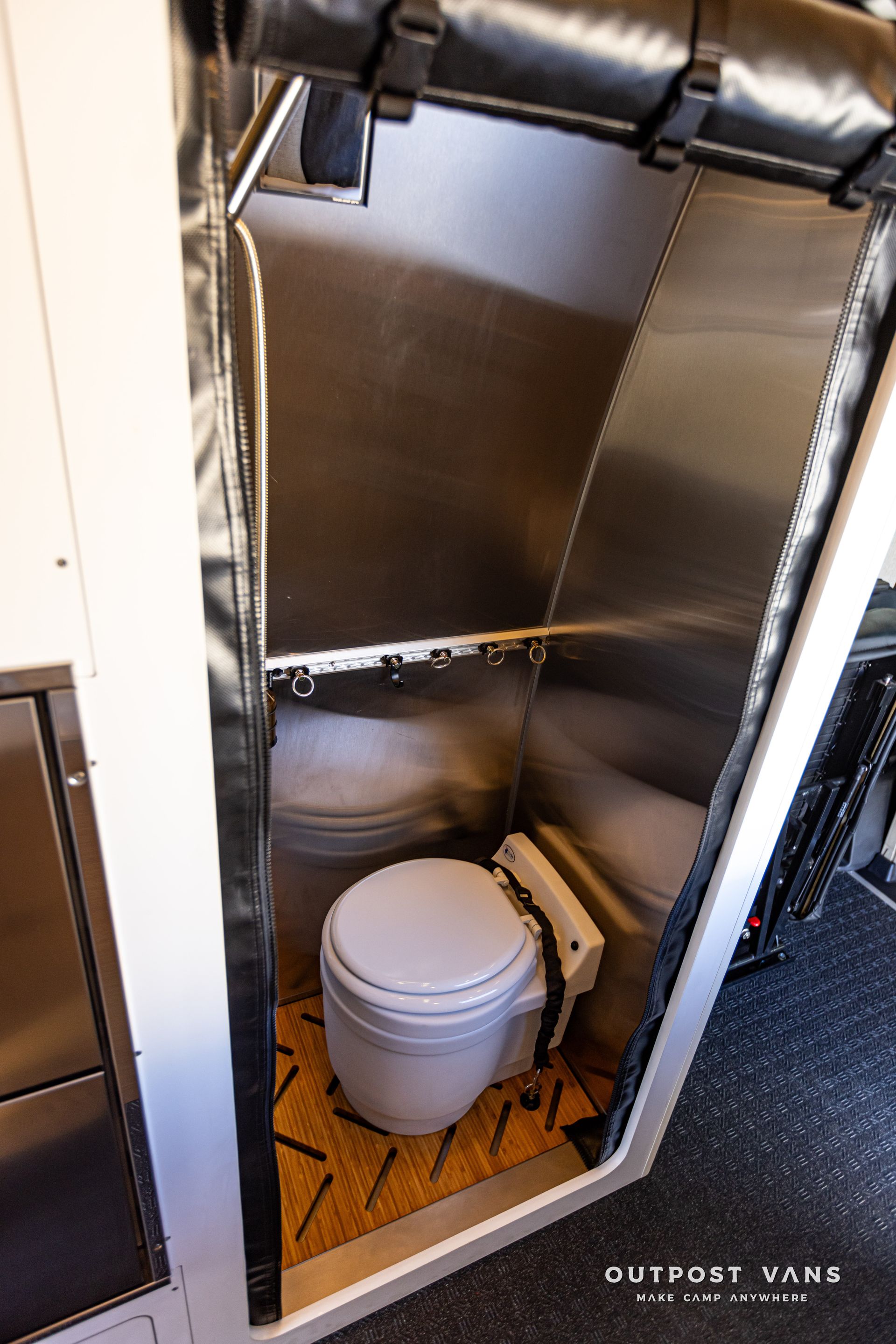 A toilet in a stainless steel bathroom in a van.
