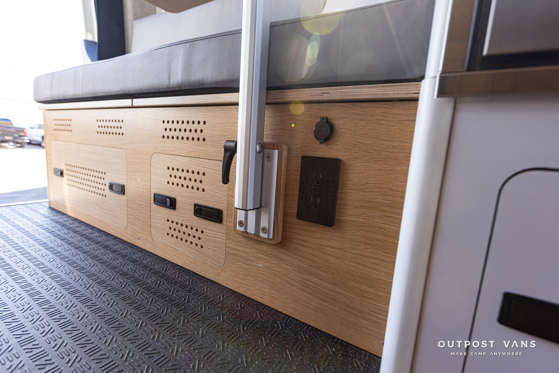 The back of a camper van with a couch and drawers underneath it.