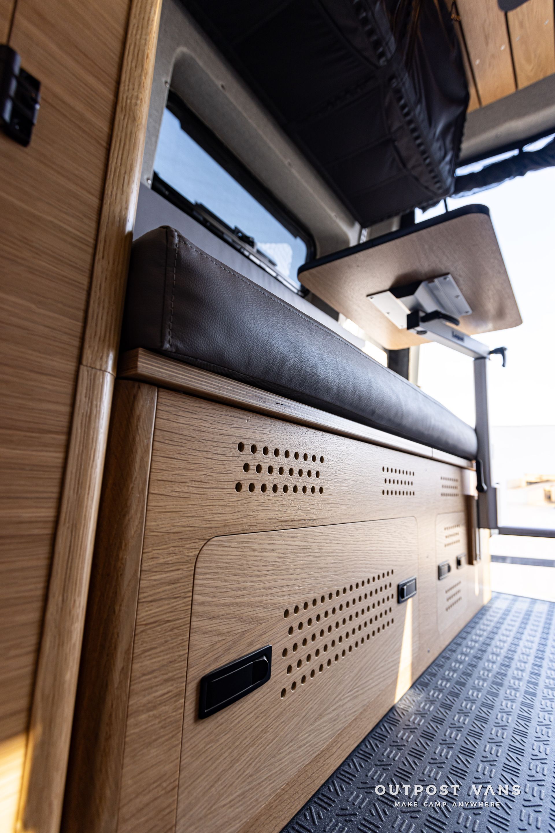 A wooden cabinet with a table on top of it in a van.