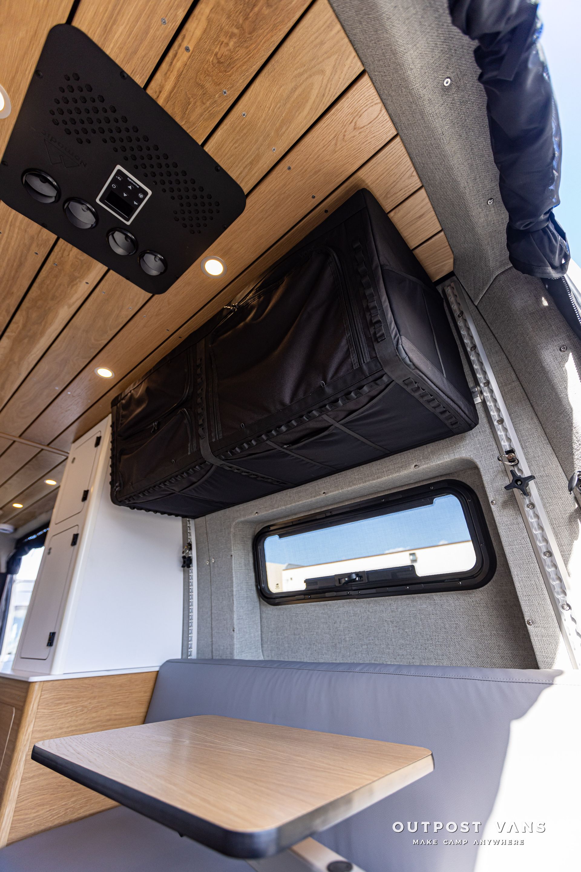 A camper van with a table and a bag hanging from the ceiling.