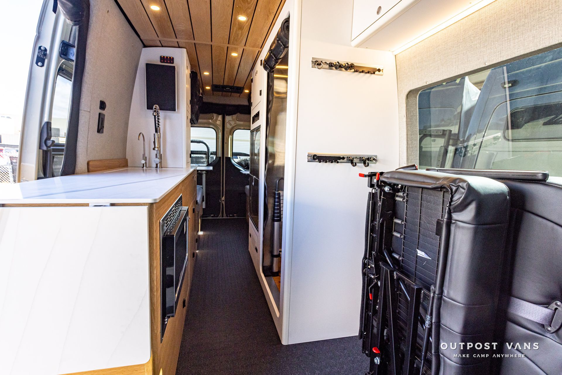 The inside of a van with a mattress on the back seat.