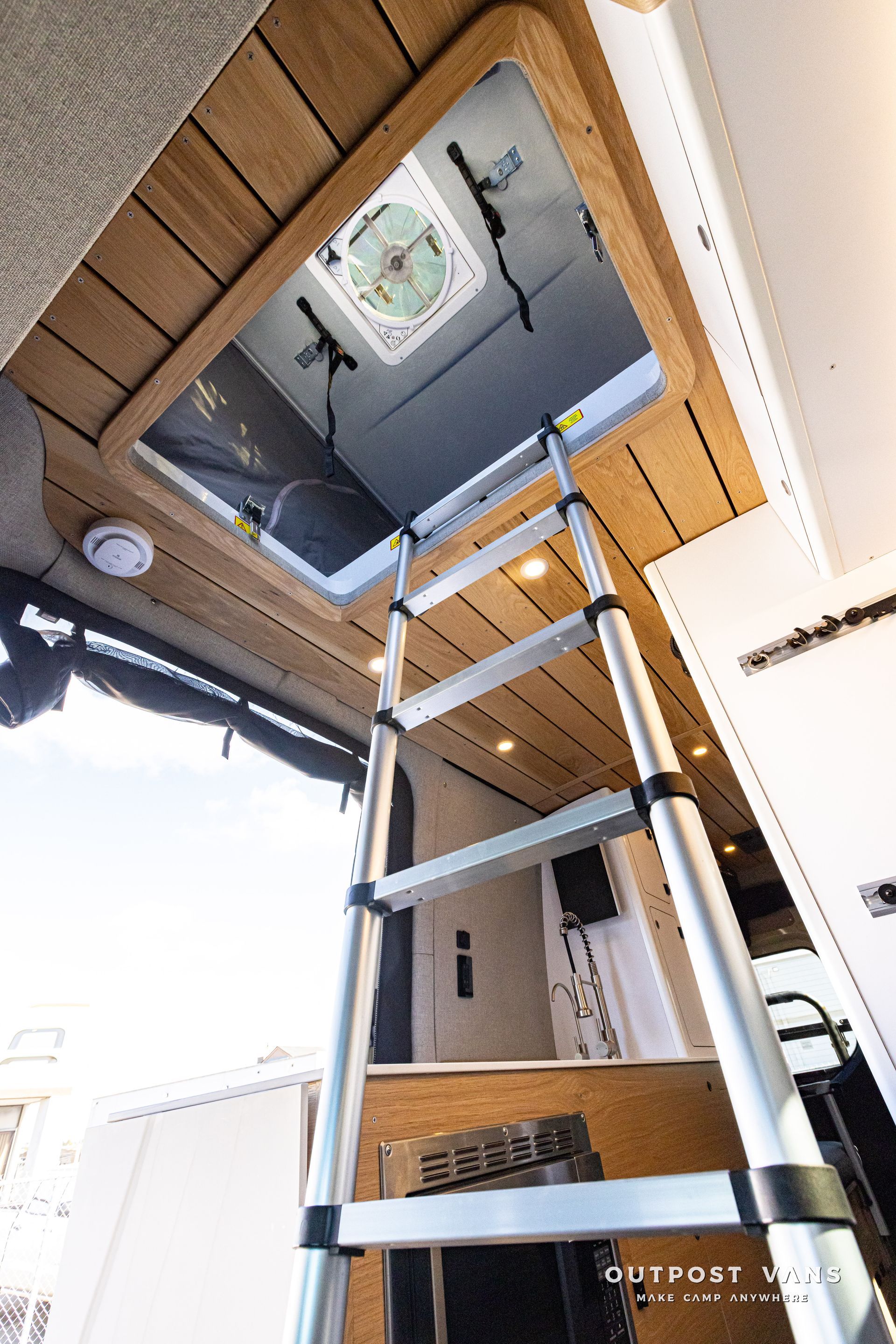 A ladder is going up to the roof of a van.